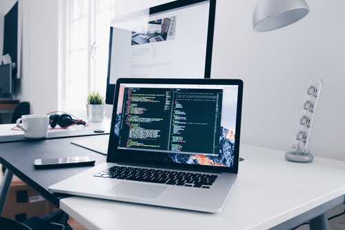 A laptop with a coding window open in a studio room